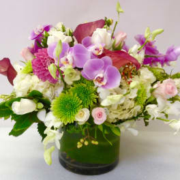 Mixed bouquet of orchids, roses, and chrysanthemums in a glass vase