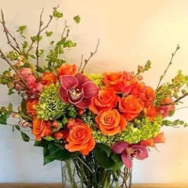 Orange roses and pink orchids in a glass vase