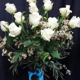 White roses in a glass vase with a blue polka-dot ribbon