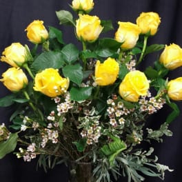 Yellow roses arranged in a glass vase with a ribbon