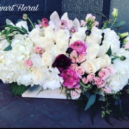 Large white and pink floral arrangement with roses and orchids