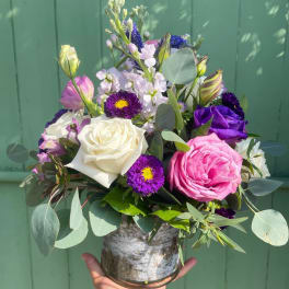 Mixed bouquet of roses and purple flowers in a glass vase