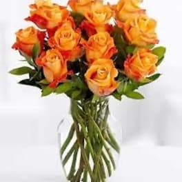Bouquet of orange and yellow roses in a clear glass vase