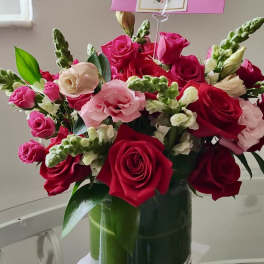 Pink and red roses with white snapdragons in a glass vase