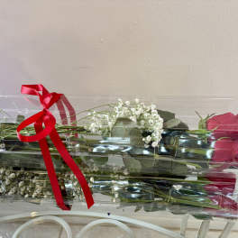 Two wrapped bouquets of red roses with baby's breath and a red ribbon