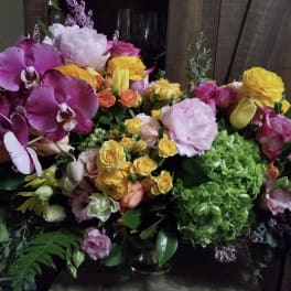 Mixed bouquet with purple orchids, yellow roses, and pink blooms