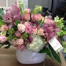 Pink orchids and roses arranged in a white vase