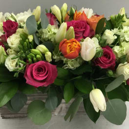 Mixed bouquet of pink roses, white tulips, and pale hydrangeas in a rectangular container