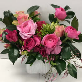 Pink and peach rose bouquet in a white container