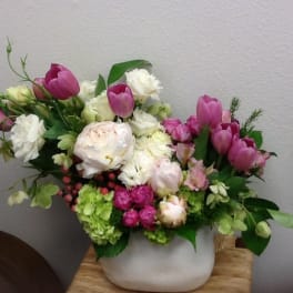 Pink tulips and white flowers arranged in a white vase