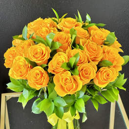 Bouquet of yellow roses with green foliage in a glass vase