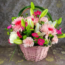 Pink basket of mixed flowers with lilies, roses, and carnations