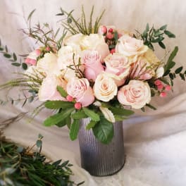 Pink and white roses arranged in a tall metal vase