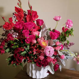 Pink and red mixed flower arrangement in a white vase