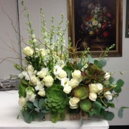 White roses and green succulents in a low rectangular arrangement