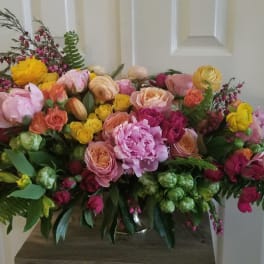 Large bouquet of pink, yellow, and peach flowers in a vase