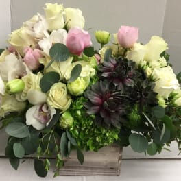 Mixed bouquet of white and pink roses with dark succulents in a wooden box