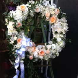 Heart-shaped floral wreath with white and peach roses and a lavender ribbon