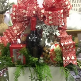 Christmas gift basket with wine, snacks, and red patterned bows
