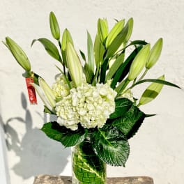 White hydrangeas and unopened lilies in a glass vase