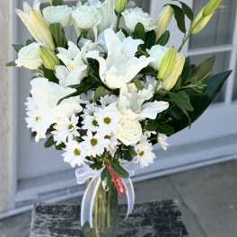 White lilies, roses, and daisies in a glass vase