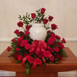 Red rose arrangement in a white vase with a large red ribbon