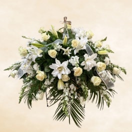 White lilies and cream roses arranged on a standing spray with ribbon