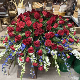 Large red rose arrangement with blue and white flowers in a low container