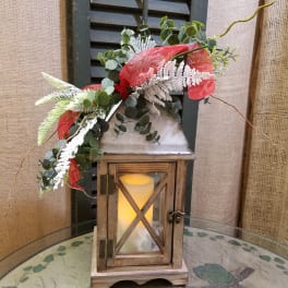 Lantern with greenery and red ribbon on a table