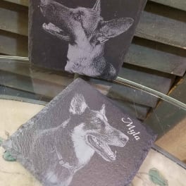 Two personalized slate plaques with dog portraits and names.