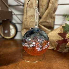 Glass ornament with blue and orange swirls hanging on a metal stand