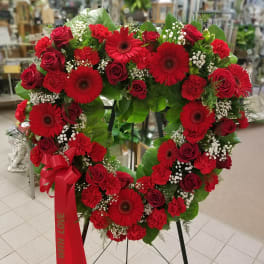 Heart-shaped red floral wreath on an easel with a red ribbon
