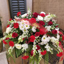 Red and white floral arrangement with a red ribbon reading Father