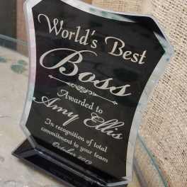 Black acrylic award plaque with silver lettering on a clear base