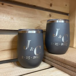 Two engraved black tumblers with initials and a date