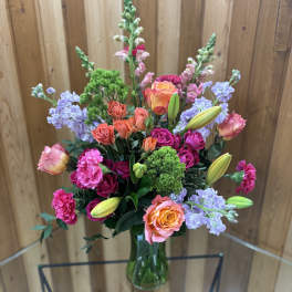 Mixed bouquet in a glass vase with roses, lilies, and pink blooms