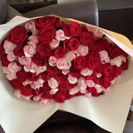 Large bouquet of red and pale pink roses wrapped in white paper