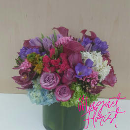 Mixed bouquet of purple, pink, and white flowers in a green vase