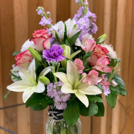 Bouquet of lilies, roses, and purple flowers in a glass vase