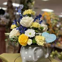 Bouquet of mixed flowers in a gray polka-dot elephant vase with a baby sign