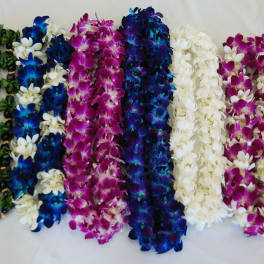 Several colorful orchid leis laid out in rows on a white surface