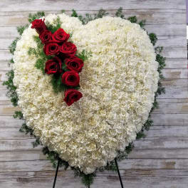 Heart-shaped white floral spray with red roses on a stand