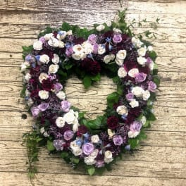 Heart-shaped floral wreath with purple, white, and burgundy roses