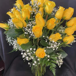 Yellow roses arranged in a clear glass vase with baby's breath