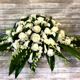 White roses and calla lilies arranged with orchids and broad leaves