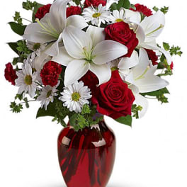 Red roses and white lilies in a red glass vase