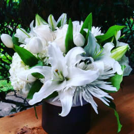 White lilies and white blooms in a black vase