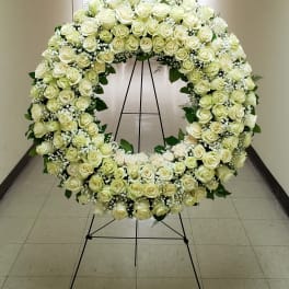 Large circular wreath of white roses on a black stand