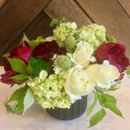 Bouquet of white and red roses with pale green hydrangeas in a black vase