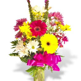 Mixed bouquet of bright daisies in a glass vase with a pink ribbon